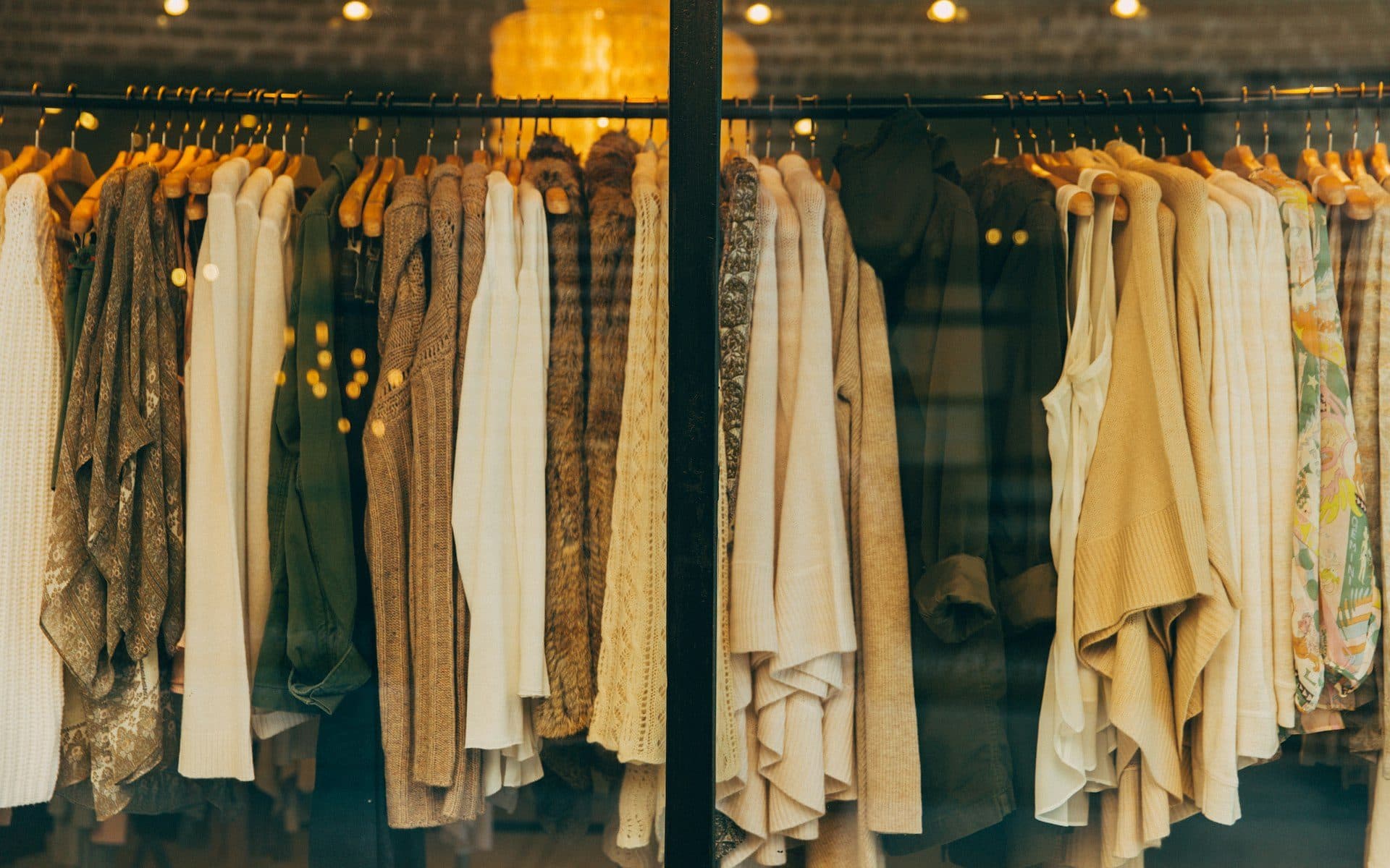 A shop window rail of linen and wool garments in earthy tones
